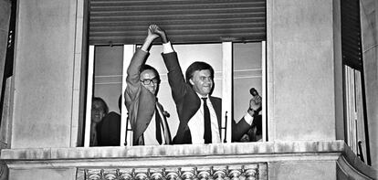 Alfonso Guerra levanta la mano de Felipe Gonz&aacute;lez, asomados ambos a una ventana del hotel Palace de Madrid, celebrando la hist&oacute;rica victoria del PSOE en las elecciones de 1982.  
 