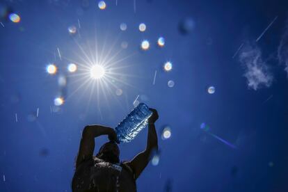 A man pours cold water onto his head to cool off