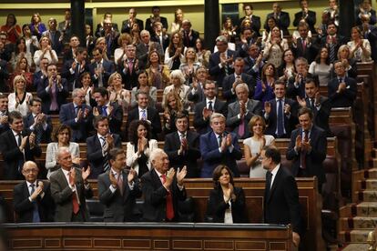 El presidente del Gobierno en funciones, Mariano Rajoy (d), recibe los aplausos de los parlamentarios del PP puestos en pie en sus escaños del Congreso de los Diputados, durante la sesión de investidura en la que logró los votos necesarios para revalidar su presidencia, el 29 de octubre de 2016.