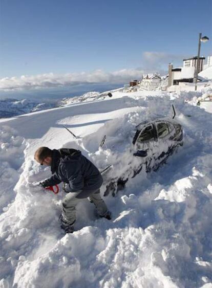 Un hombre intenta sacar su coche, atrapado en Sierra Nevada.