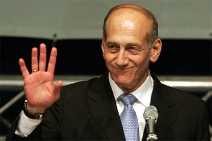 Ehud Olmert saluda a sus partidarios en la sede del partido Kadima con un retrato de Ariel Sharon al fondo.