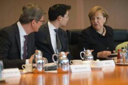 La canciller alemana, Angela Merkel (dcha), conversa con el ministro germano de Economía, Philipp Rösler (c), y con el titula de Exteriores, Guido Westewelle (izq), hoy antes del comienzo de la reunión semanal del Consejo de Ministros.