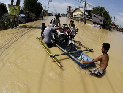 Un grupo de filipinos usa una canoa de fabricación casera para trasladar una moto en una zona que resultó inundada tras el paso del tifón Koppu por la ciudad de Calumpit, en la provincia de Bulacan, al norte de Manila (Filipinas).