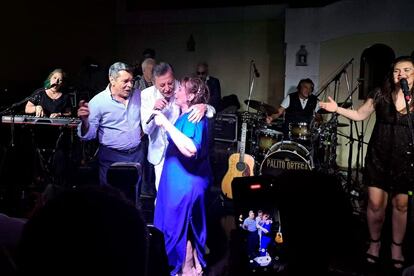 Jorge Olivera abraza a un músico y a su esposa durante una fiesta por el aniversario matrimonial de los dos.