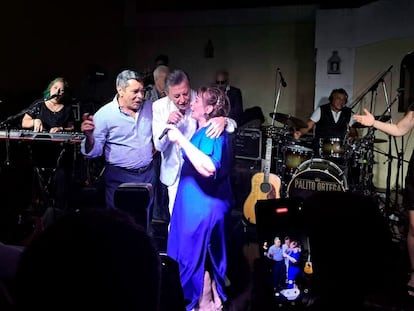 Jorge Olivera abraza a un músico y a su esposa durante una fiesta por el aniversario matrimonial de los dos.