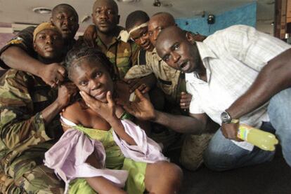 Soldados leales al presidente electo de Costa de Marfil, Alassane Ouattara, se fotografían con Simone (c), esposa del presidente saliente, Laurent Gbagbo, tras su captura en una habitación del Hotel Golf de Abiyán, Costa de Marfil, hoy lunes 11 de abril de 2011.