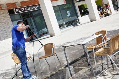 A restaurant worker in Madrid disinfects tables and chairs, ahead of the reopening of street cafés in the region on Monday.