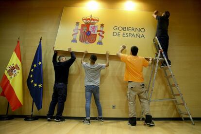 Operarios colocan un cartel de Gobierno de España momentos antes de la entrega de las carteras de Ciencias a Pedro Duque, Economía a Nadia Calviño e Industria a Reyes Maroto en el ministerio de Economía en Madrid.