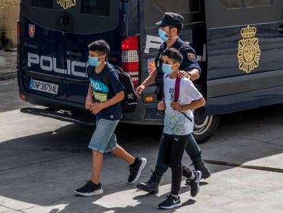 Un policía nacional acompaña a dos menores, el pasado 20 de mayo, en Ceuta.