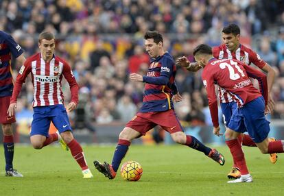 Leo Messi se dispone a pasar un balón rodeado por tres jugadores del Atlético de Madrid: Antoine Griezmann (i), Carrasco y Augusto Fernández.