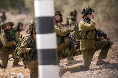 Un soldado se tapa los ojos mientras vigila junto a otros compañeros una carretera cerca del kibutz de Kfar Aza, cerca de la frontera con Gaza, este miércoles.