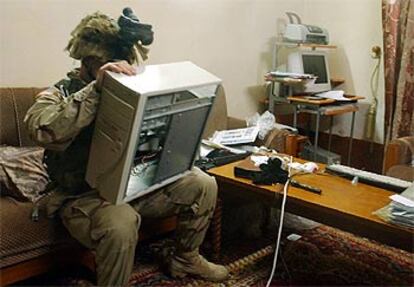 Un soldado estadounidense retira el disco duro de un ordenador durante los registros de ayer en Tikrit (Irak).