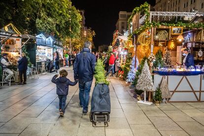 Un hombre camina con su hijo por el Mercado de Navidad de Santa Lucía, en Barcelona.