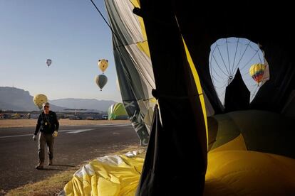 Un hombre pasa junto a uno de los más de 60 globos que participan en el 23º European Balloon Festival.