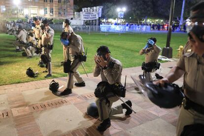 Los agentes de policía se colocan máscaras para evitar ser rociados con gases o líquidos en la cara, antes de enfrentarse con los manifestantes y contramanifestantes en el campus de la UCLA.