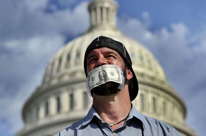 Un hombre protesta con un billete de dólar en la boca durante una concentración en el Capitolio en Washington, 1 de octubre de 2013. El presidente de EE.UU., Barack Obama, recibirá en la Casa Blanca a los principales líderes republicanos y demócratas en el Congreso para abordar el cierre parcial de la Administración federal por falta de fondos, que ha entrado en su segundo día.