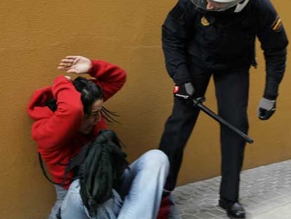 Una joven que se resistió a abandonar el edificio sale del escoltada por la policía.