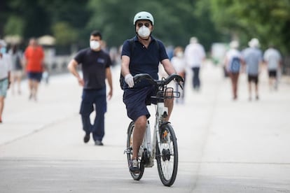 Un hombre con mascarilla y guantes monta en una BiciMad por el Retiro, el pasado 31 de mayo. 