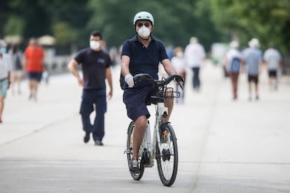 Un hombre con mascarilla y guantes monta en una BiciMad por el Retiro, el pasado 31 de mayo.