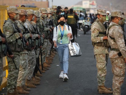 Durante las primeras horas del toque de queda, una mujer camina entre un cerco militar en Lima, este martes.