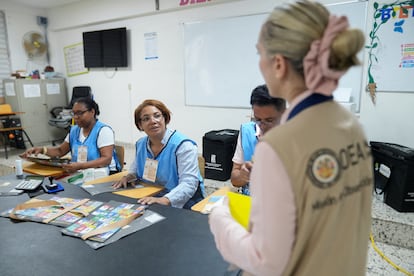 Una observadora electoral de la Organización de Estados Americanos (OEA) habla con funcionarios electorales en un centro de votación de Santo Domingo.