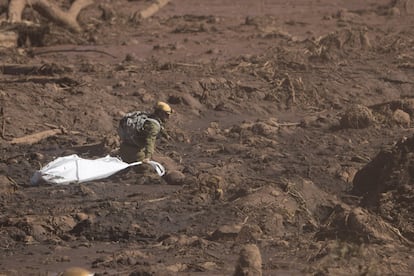 Un especialista del equipo de rescate israelí camina sobre el lodo con una bolsa vacía para trasladar un cuerpo sin vida.