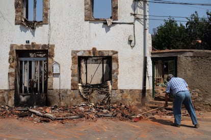 Un vecino limpia los escombros de una de las casas arrasadas por el fuego en el municipio de Quintana y Congosto, en la provincia de León.