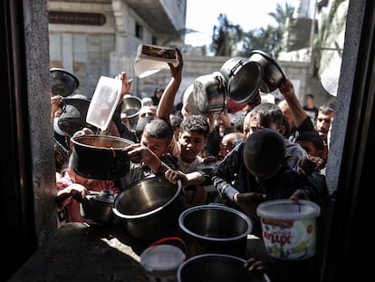 Gazatíes llevan recipientes vacíos a un comedor de caridad, el 29 de febrero en Deir al Balah (Gaza).