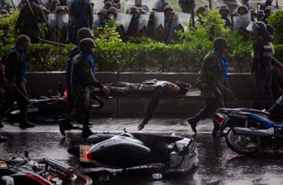 El cuerpo del soldado muerto durante el choque entre los <i>camisas rojas</i> y el Ejército en las calles de Bangkok es evacuado por sus compañeros.