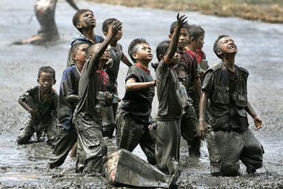 Niños indonesios piden ayuda a los helicópteros que sobrevuelan los alrededores de Banda Aceh.