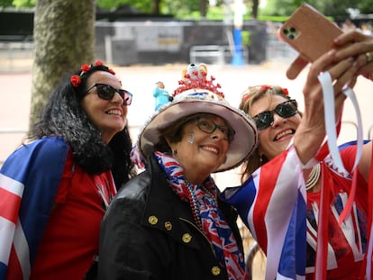 Tres mujeres ataviadas con la bandera del Reino Unido se hacen fotos este miércoles en The Mall, la avenida que conduce al Palacio de Buckingham