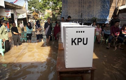 La gente hace cola para votar en un colegio electoral inundado después de una fuerte lluvia en Banding, Java Occidental.
