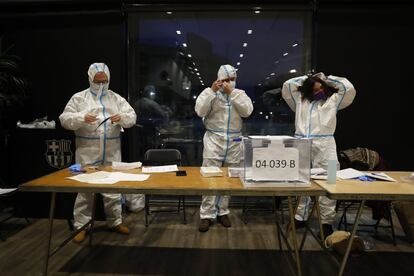 Miembros de una mesa electoral se ponen los trajes EPI a las 19.00, en el auditorio del Camp Nou. A partir de esa hora pueden acudir a votar aquellas personas que estén infectados por coronavirus o que sean contactos estrechos de afectados por covid-19.