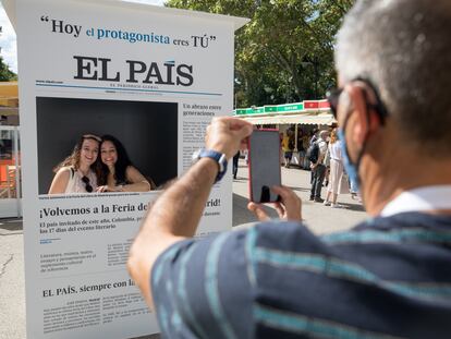 Dos visitantes de la Feria del Libro de Madrid se toman una foto con la portada de EL PAÍS.
