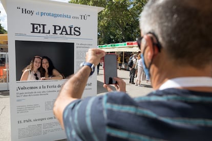 Dos visitantes de la Feria del Libro de Madrid se toman una foto con la portada de EL PAÍS.