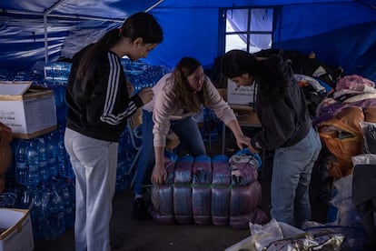 Tres mujeres trabajadoras sociales desempacan ropa donada para personas refugiadas en una escuela en la localidad de Deir Al-Ahmar, en el norte de Líbano, el 2 de noviembre de 2024.