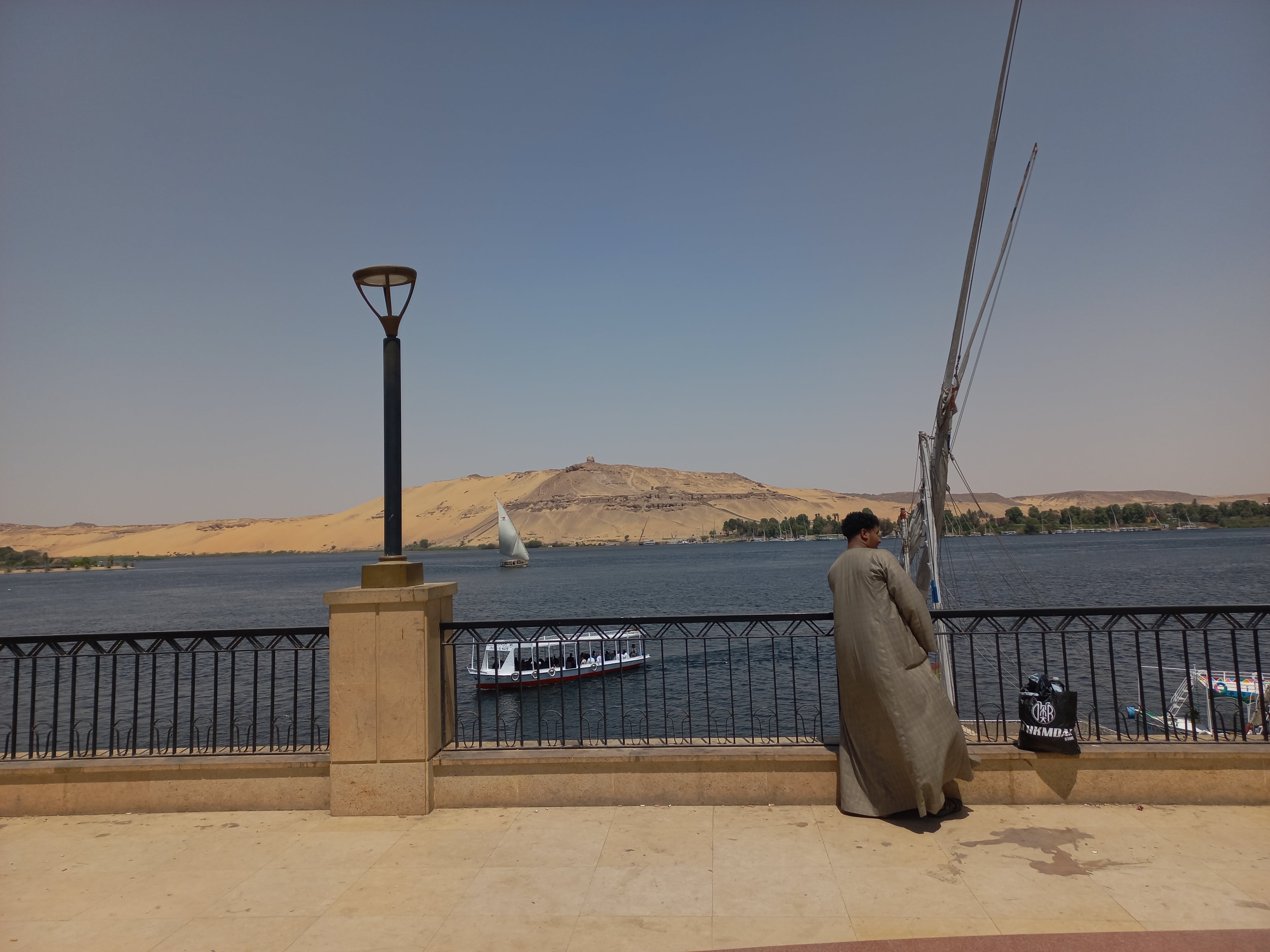 Un hombre en galabeya habla por teléfono en el paseo marítimo de Asuán, frente al río Nilo, el pasado 12 de julio.