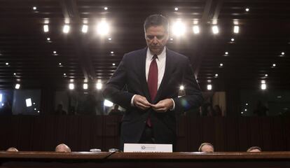 El exdirector del FBI James Comey se ajusta la chaqueta antes de testificar.