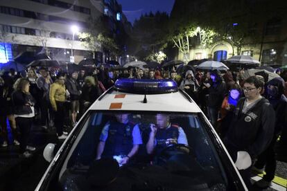 Un coche de los Mossos d'Esquadra rodeado de ciudadanos en el exterior de un colegio electoral en Figueres, en Girona. 