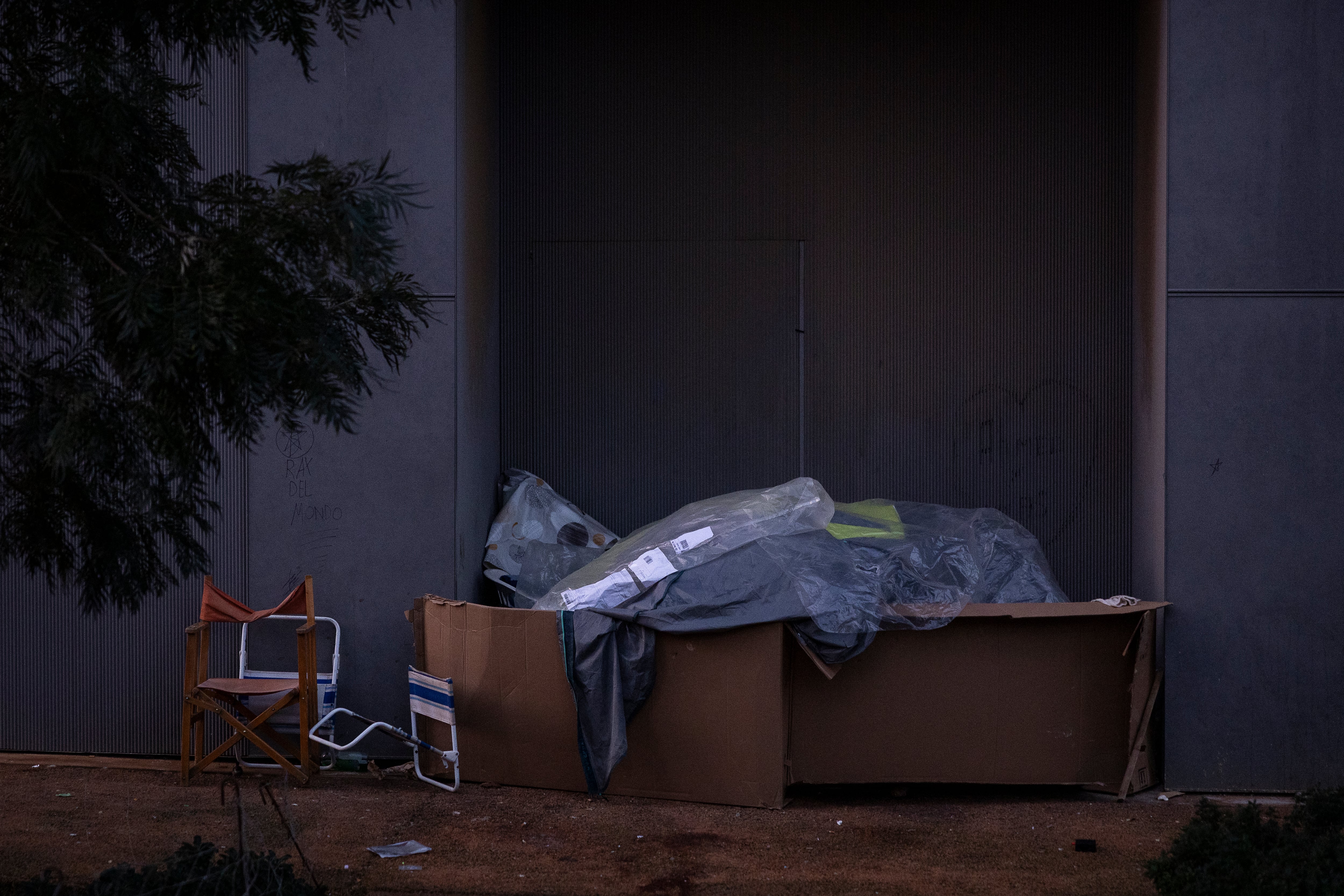 En la imagen, una persona sin hogar se refugia del frío para pasar la noche con la ayuda de cartones en Badalona.