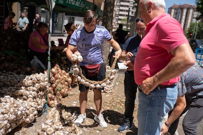 Zamora. Un joven vendedor retuerce una ristra de ajos para meterla en la bolsa.