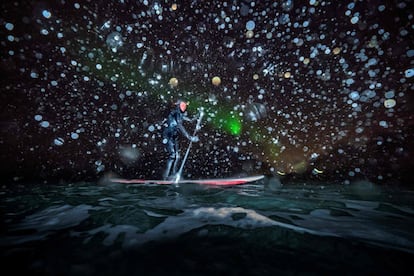 Myrtille Heissat faz padel surf sob uma aurora boreal em Unstad, nas Ilhas Lofoten.