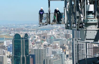 Dos trabajadores en lo alto de una estructura en Osaka.