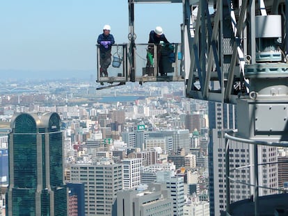 Dos trabajadores en lo alto de una estructura en Osaka.