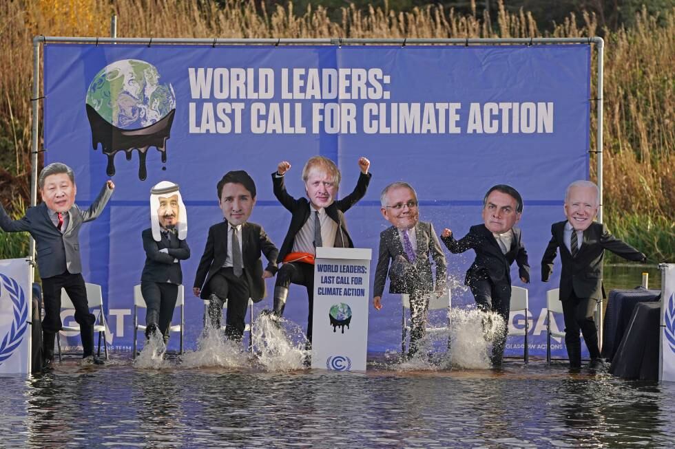 Activistas con las caretas de los líderes mundiales simulan durante la COP26 una mesa de negociación en el canal escocés de Clyde.