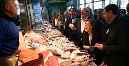 La vicepresidenta del Gobierno, Soraya Sáenz de Santamaría, acompañada de Juan Manuel Moreno, derecha, ríen con el comentario de un pescadero en una visita a un mercado de Huelva, el 10 de marzo de 2015.