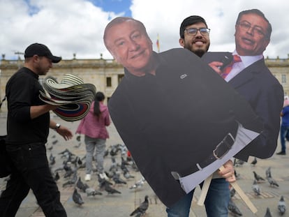 Un hombre posa sosteniendo carteles de cartón con imágenes de los candidatos a la Presidencia en Colombia en Bogotá.