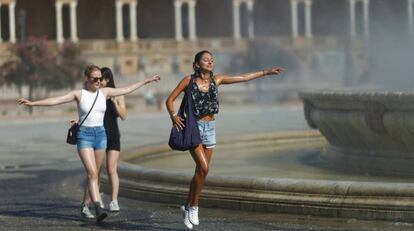 Unas chicas se refrescan en la fuente en la Plaza de España de Sevilla.