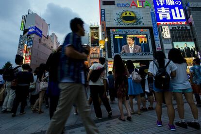 Ciudadanos japoneses escuchan el discurso del primer ministro japonés, Shinzo Abe, con motivo del 70 aniversario del fin de la participación nipona en la II Guerra Mundial, en una pantalla colocada en una calle de Tokio.