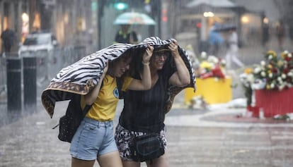 Dos mujeres intentan resguardarse en Barcelona de la tormenta del 17 de agosto. 